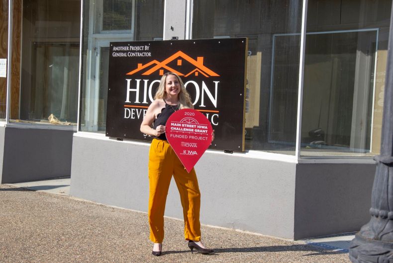 A woman standing outside a storefront holding a sign